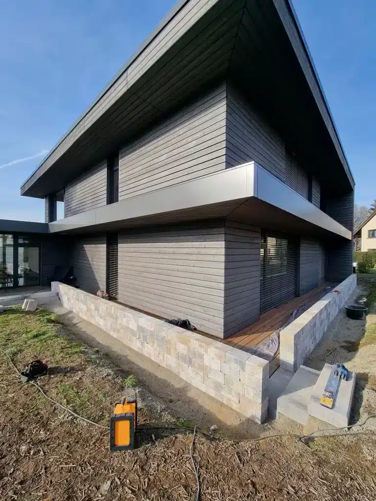 Aménagement extérieur et construction d'un muret en pierre autour d'une maison.