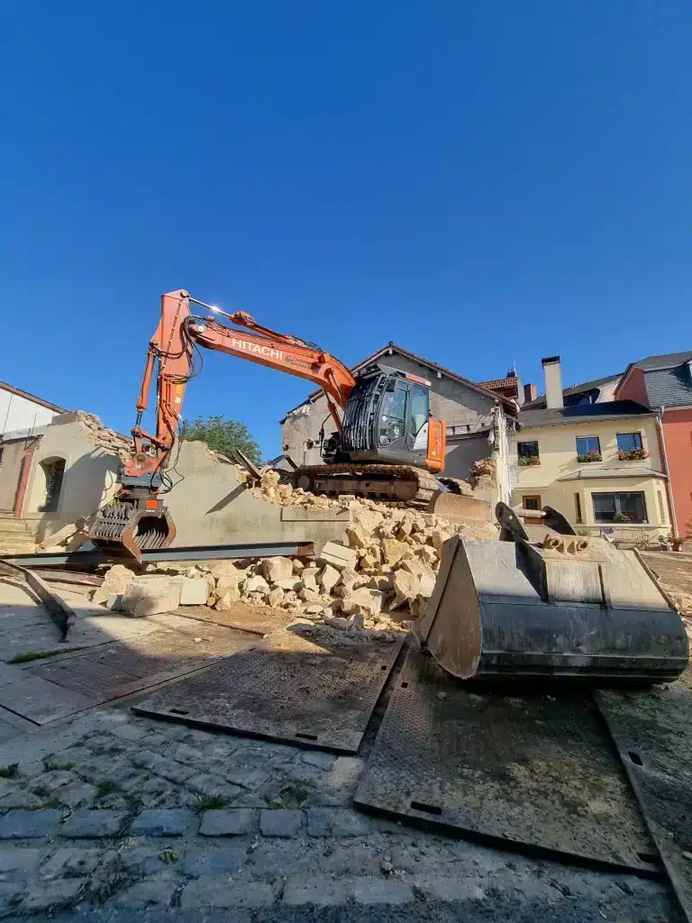 Démolition d'une maison mitoyenne avec une excavatrice de la société Demuth Travaux.