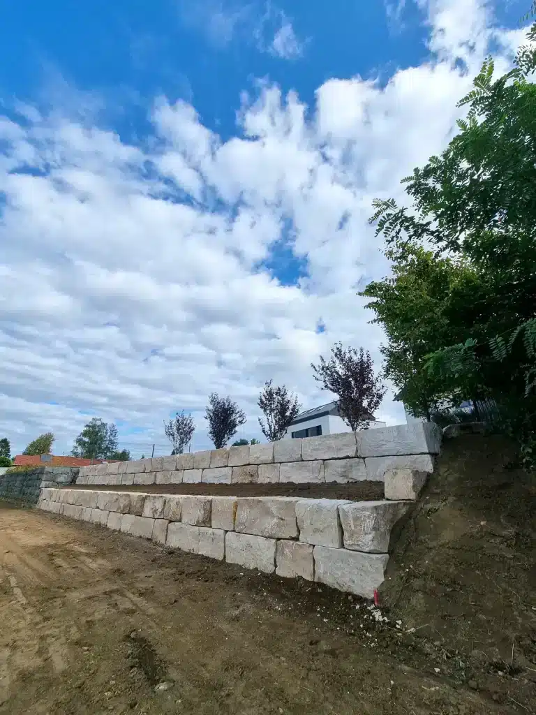 Travaux de remblayage pour éviter les glissements de terrain avec construction d'un mur en blocs de pierre naturelle.