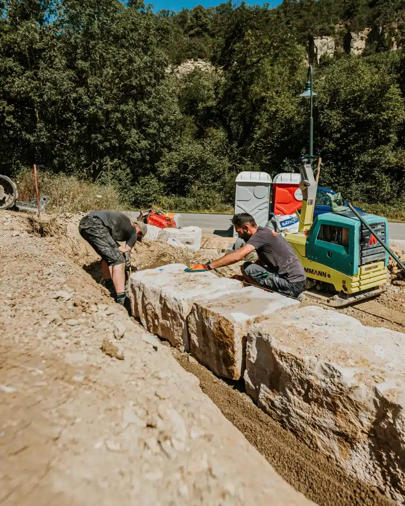 Construction d'un mur avec des blocs de pierre naturelle du Jura.