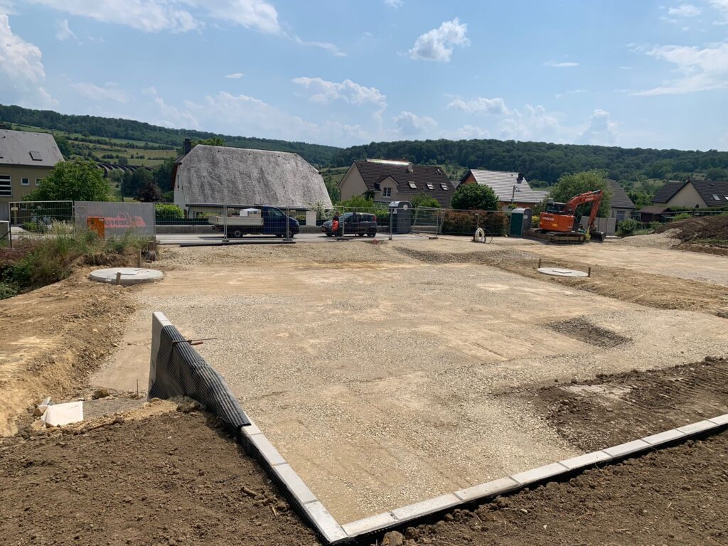 Durchführung von Aushubarbeiten mit dem Bau einer L-förmigen Mauer zur Stabilisierung des Hangs.