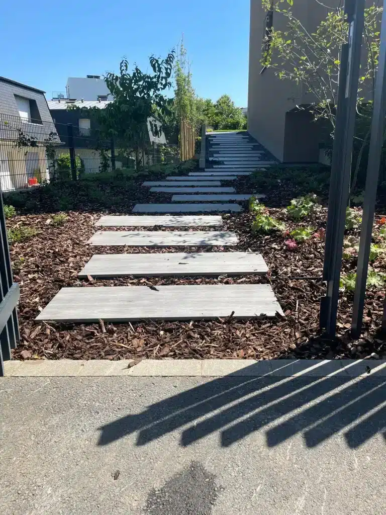 Allée de jardin avec dalles en pierre et paillage décoratif.