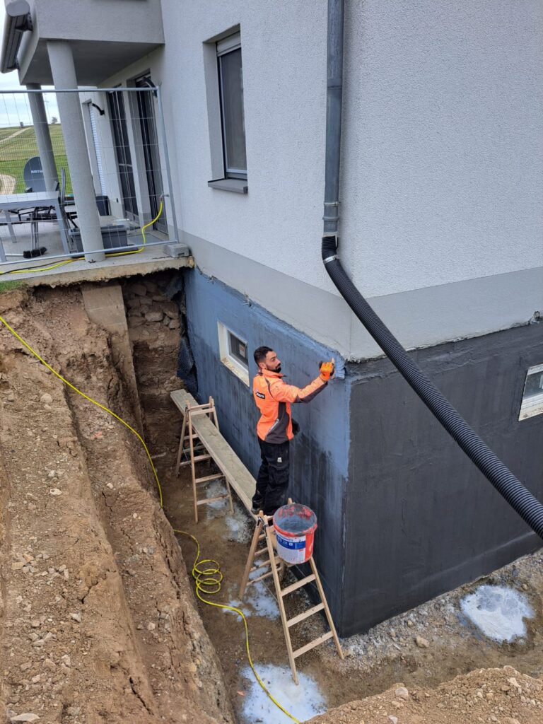 Un ouvrier en train de réaliser des travaux d'étanchéité pour un sous-sol chez un particulier.